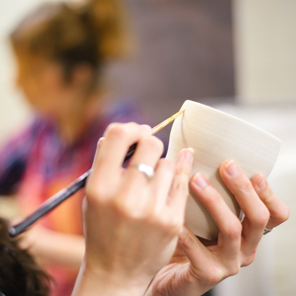 Deltager maler på keramik kop til keramik workshop.