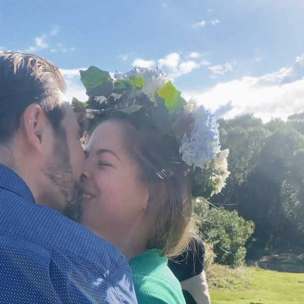 kærestepar kysser mens kvinden har en blomsterkrans på hovedet, blomsterkransen har en lavet på en kreativ workshop til en sommerfest