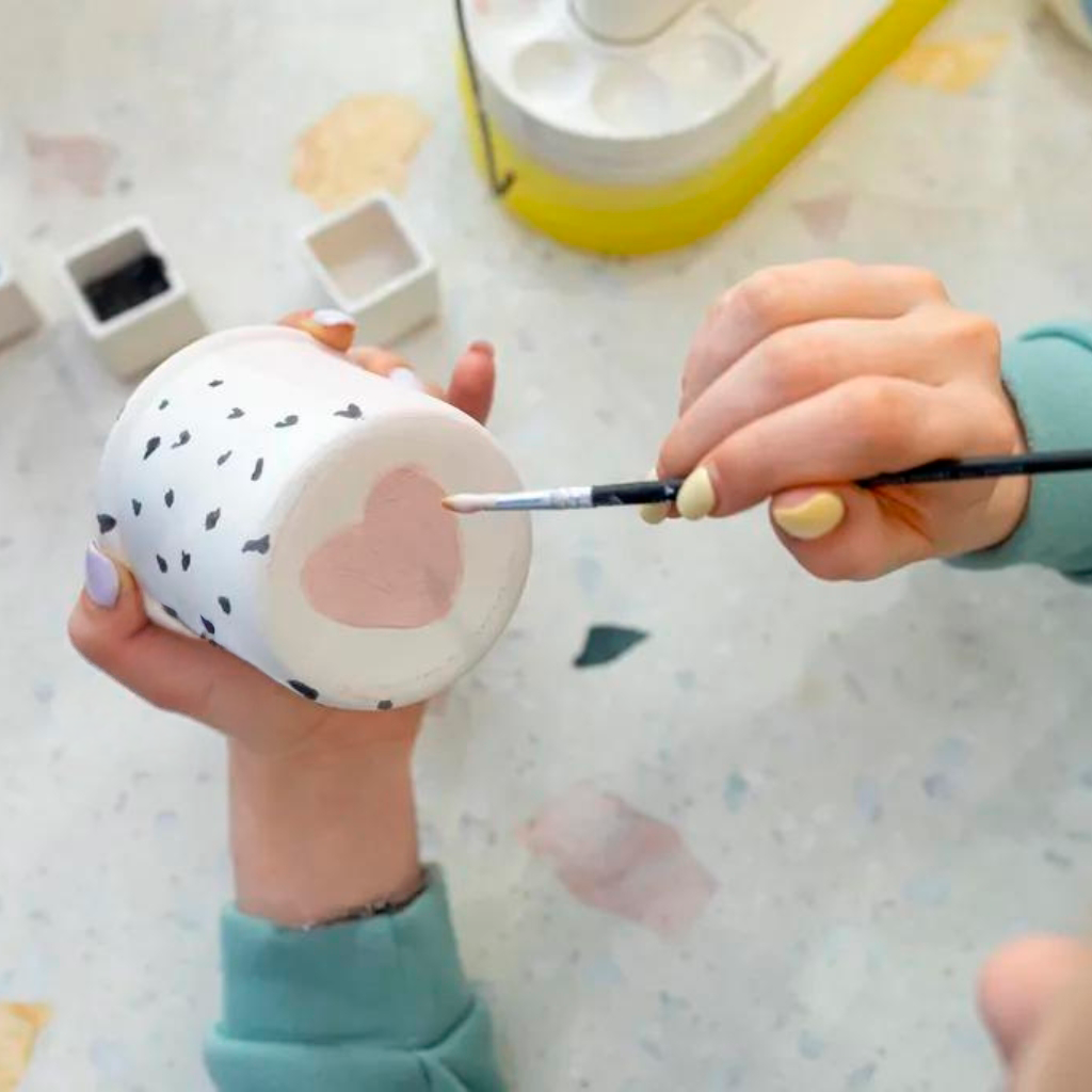 Kvinde maler på en keramikkop på kreativ workshop i Odsherred