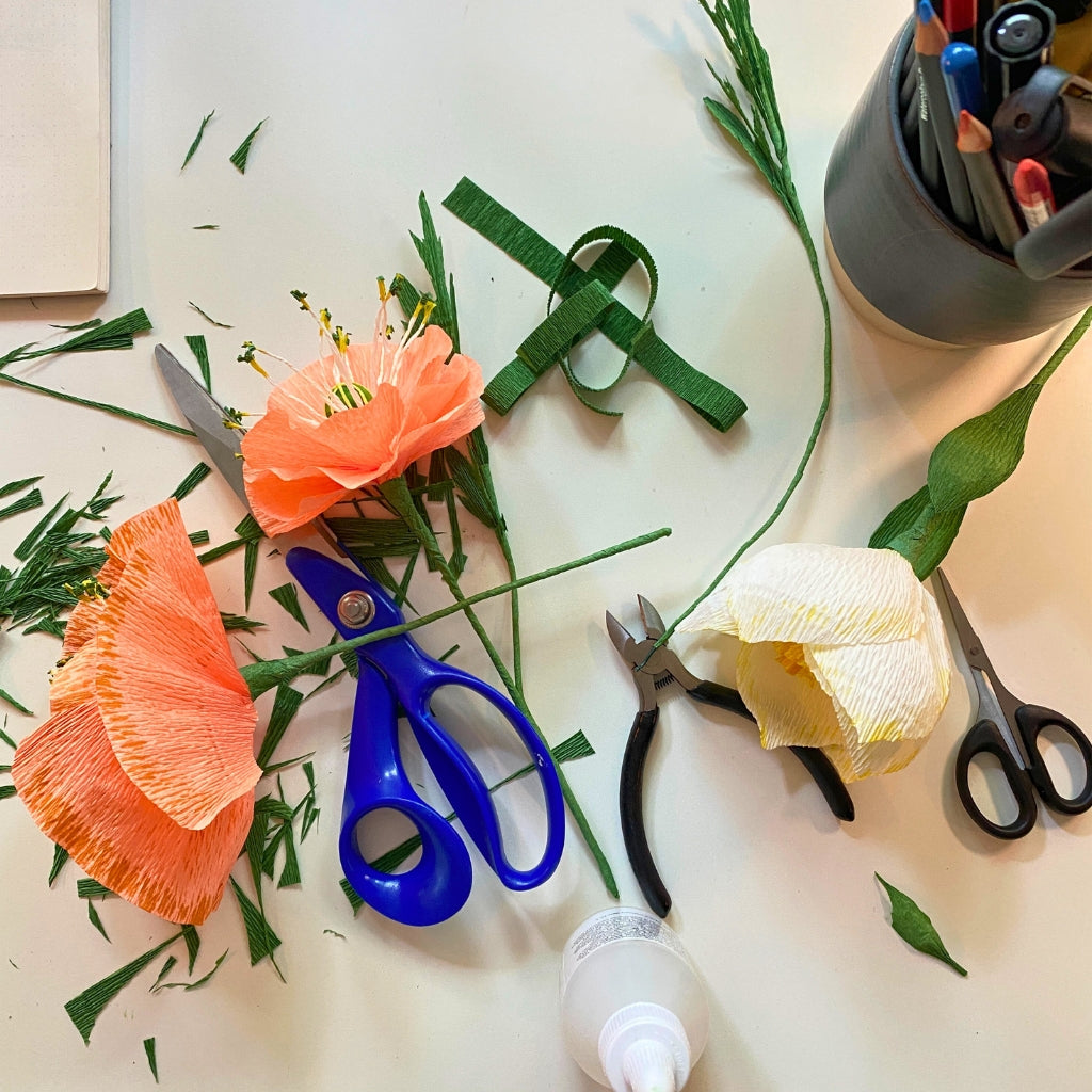 Papirblomster er ved at blive lavet med crepepapir, lim, ståltråd og saks på den kreative workshop "lav papirblomster" hos creatør i Vig, odsherred