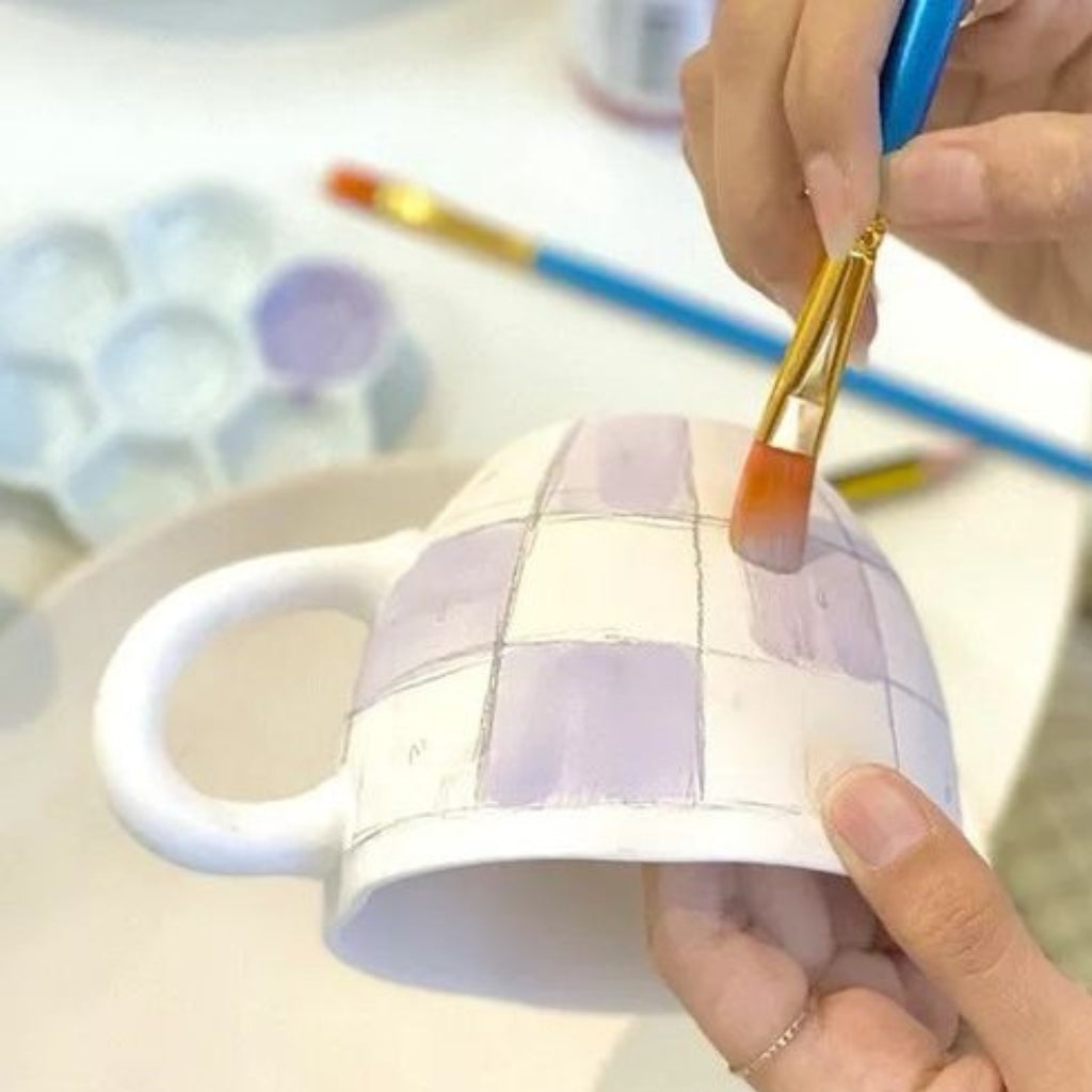 familie maler keramikkopper på mal på keramik workshop hos creatør i vig odsherred. De er med på en kreativ workshop. 