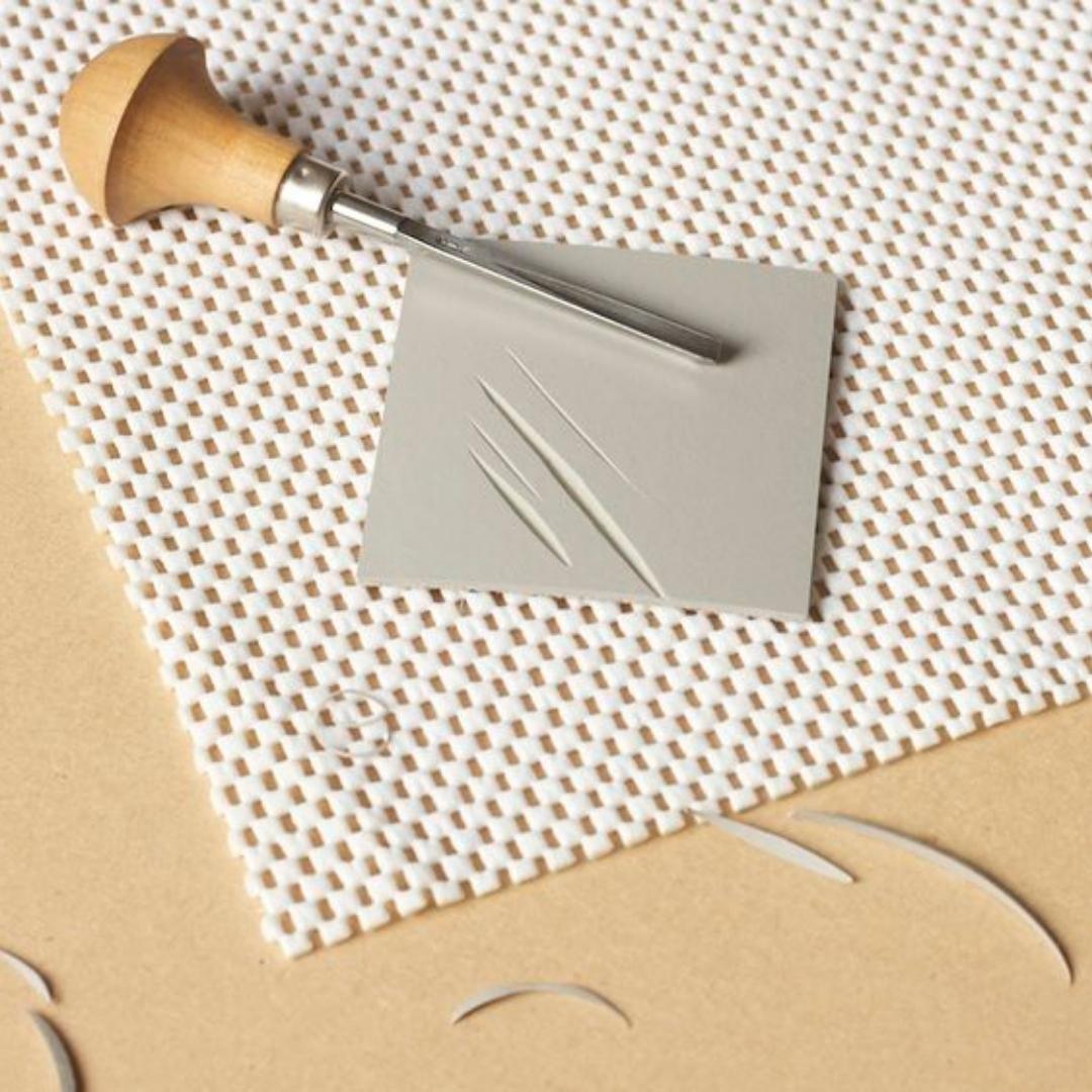 en plade af linoleum der er ved at blive skåret til et linoleumstryk på en kreativ workshop