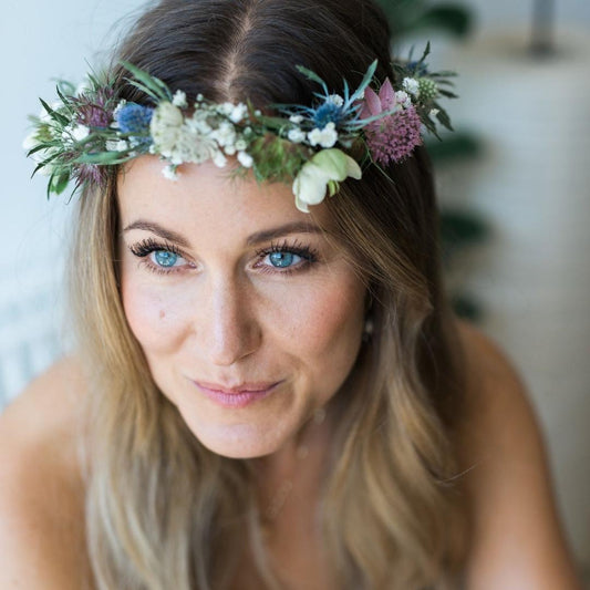 Kvinde med blå øjne har en blomsterkrans på hovedet, hun har selv lavet den til en kreativ workshop: Blomsterkrans workshop til et polterabend 