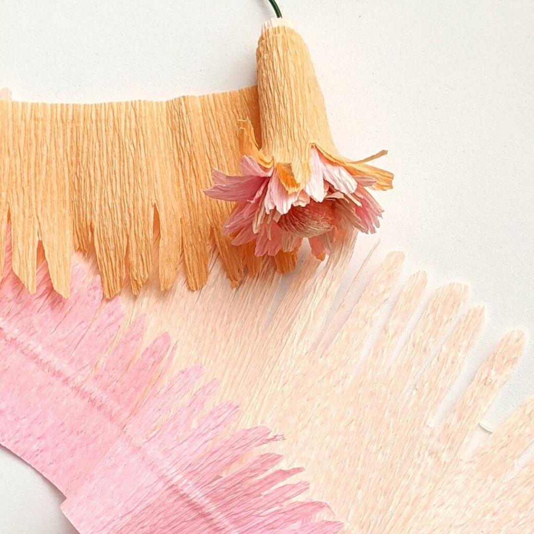 lyserød og orange papirblomst lavet af crepepapir til en kreativ workshop til en julefrokost